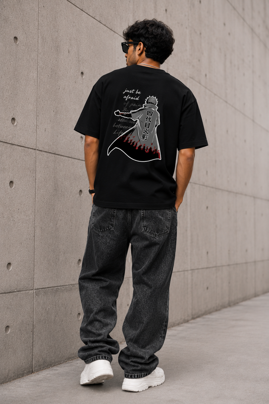 Person wearing a black t-shirt with a graphic design against a concrete wall.